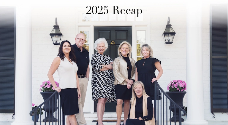 Landfall Realty team standing in front of a white brick home during the 2025 year-in-review photo.